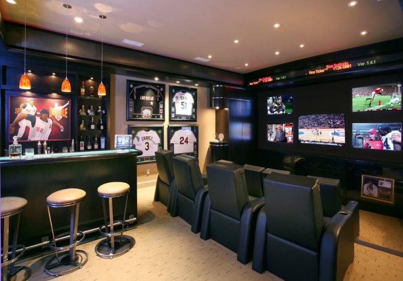 The best in man cave ideas.  A room with multiple TVs bar and hung sports jerseys on the wall.